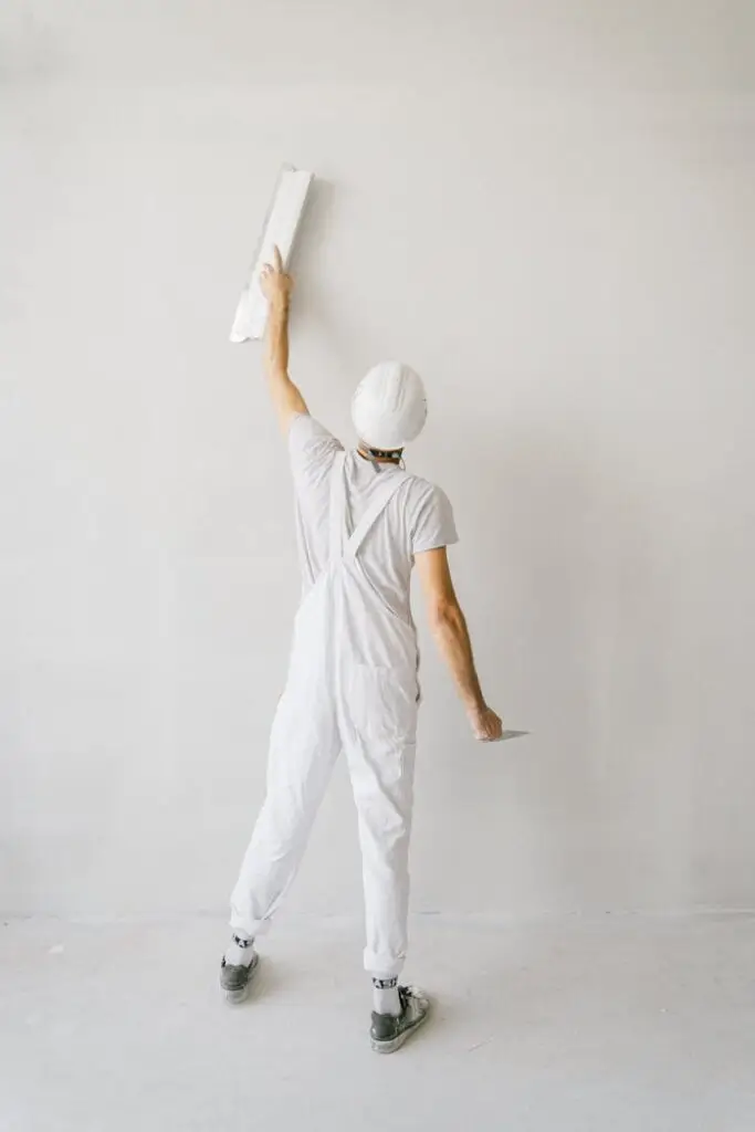 Construction Worker Working on the White Wall of a House